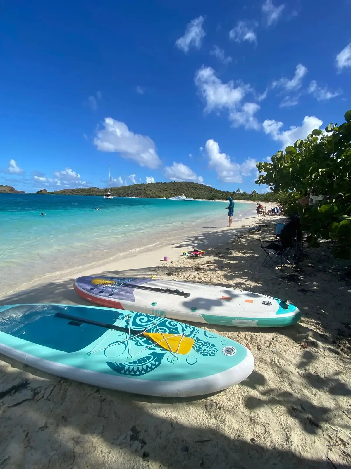 Paddle boards and beach chairs on the white sand of Playa Tortuga, Culebrita, with guests in the shallows