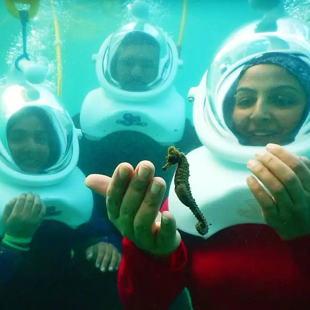 Two helmet divers underwater in San Juan, faces dry inside the dive helmets