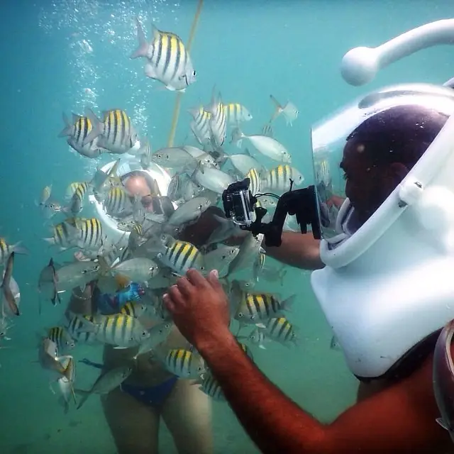Helmet diver surrounded by a school of sergeant major fish in Puerto Rico